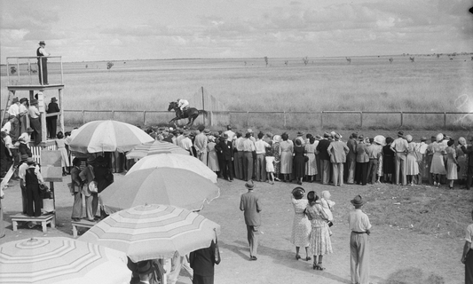 Race day in Roma, Queensland during 1950, with spectators gathered around the track at a community racing event.