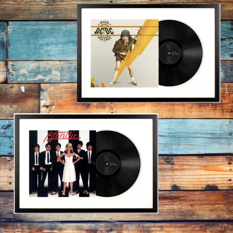 Framed AC/DC and Blondie vinyl records with album covers on a rustic wood background