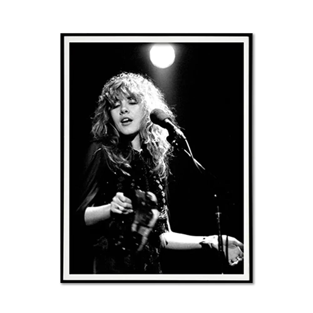 Black and white photo of a female singer with wavy hair performing on stage with a microphone.