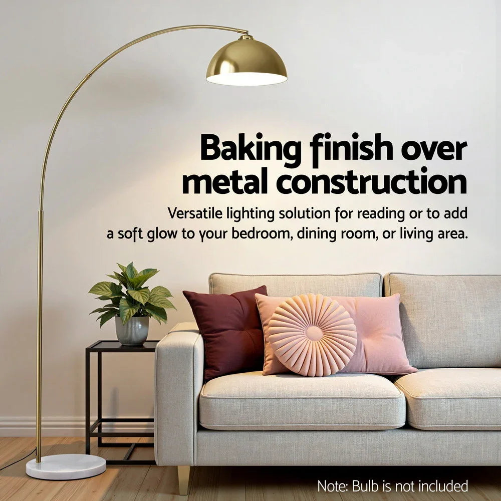 Gold arc floor lamp with marble base beside beige sofa and decorative pillows in living room
