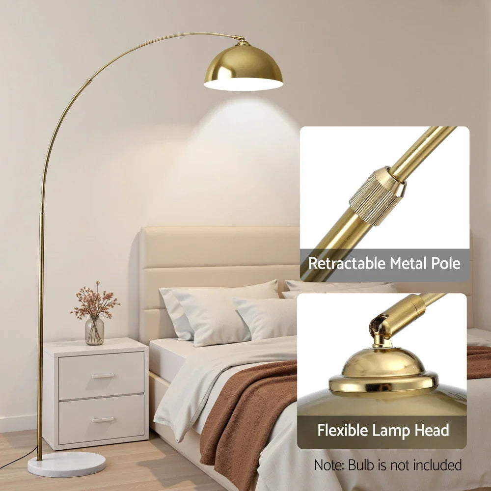 Gold arc floor lamp with retractable metal pole and flexible head beside a modern bed