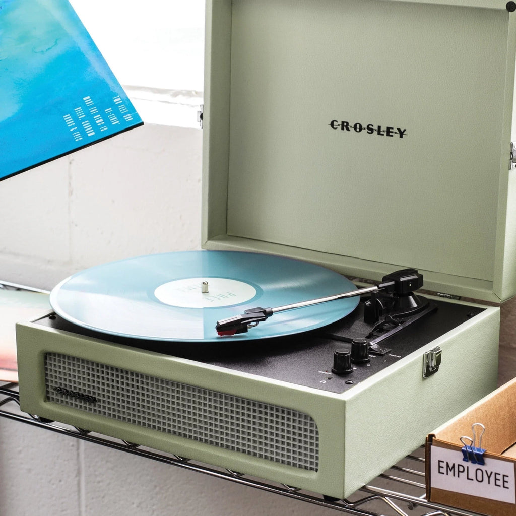 Crosley record player with blue vinyl on a metal shelf in a modern office setting