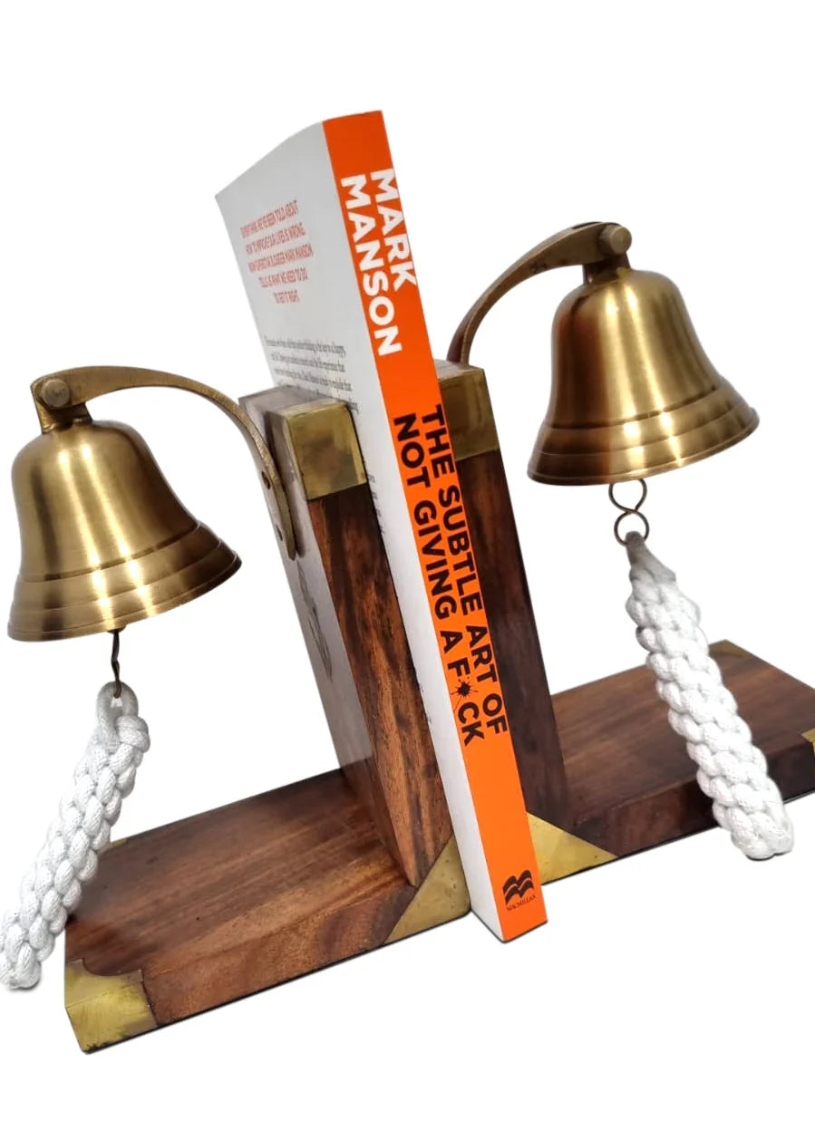 Brass bell bookends with rope, holding 'The Subtle Art of Not Giving a F*ck' book