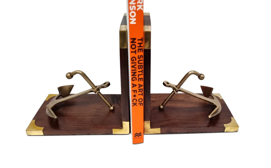 Brass anchor bookends on wooden base with a book between them, nautical decor
