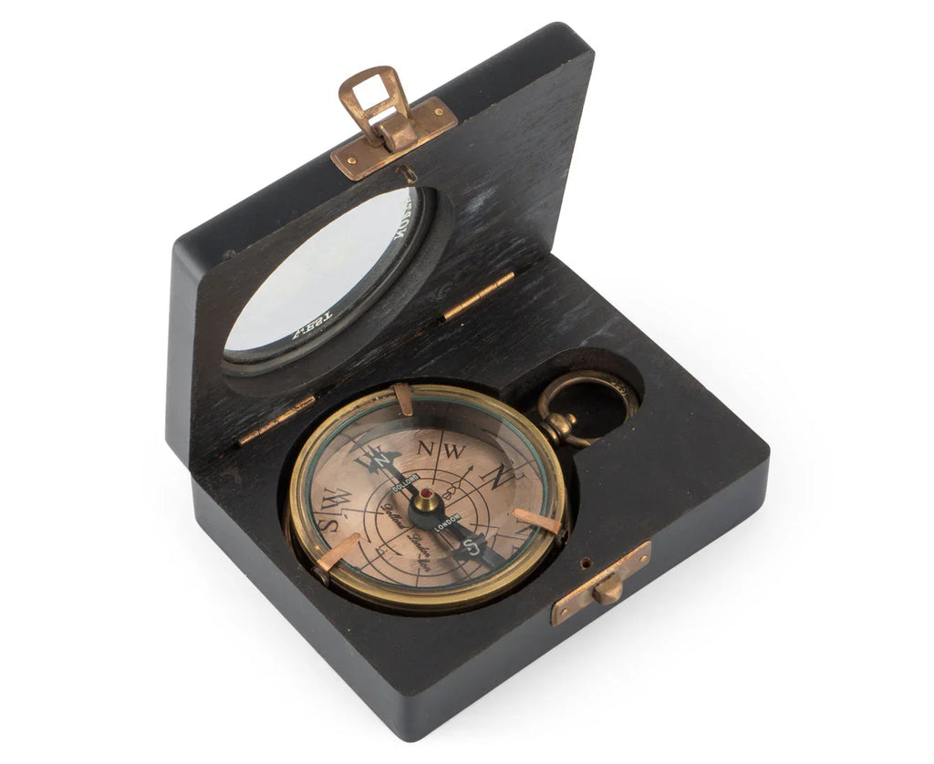Vintage brass compass in open black wooden box with glass lid