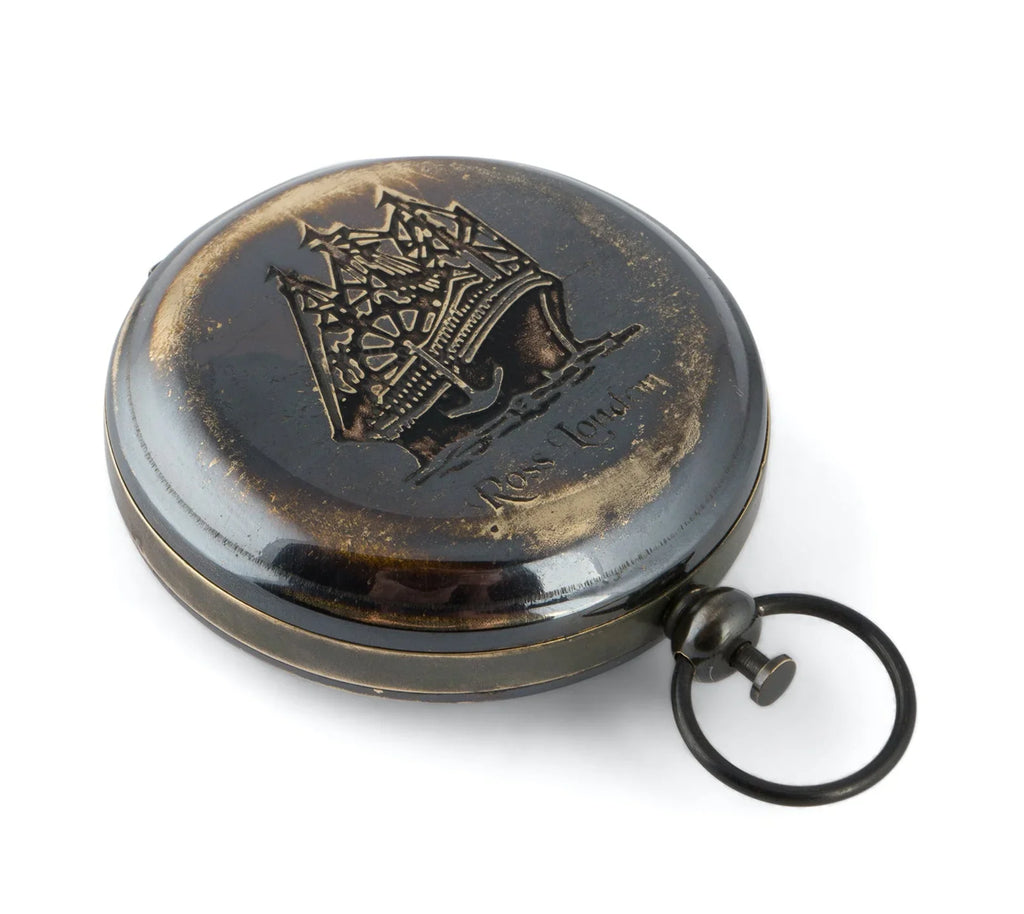 Antique metal pocket watch with engraved ship and aged bronze finish on white background