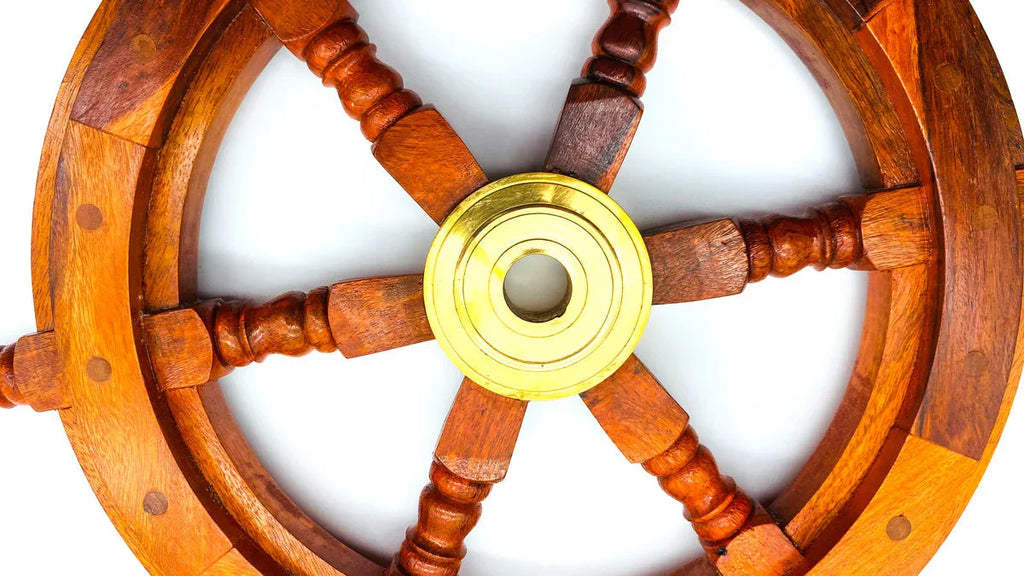 Wooden ship wheel with brass center on white background