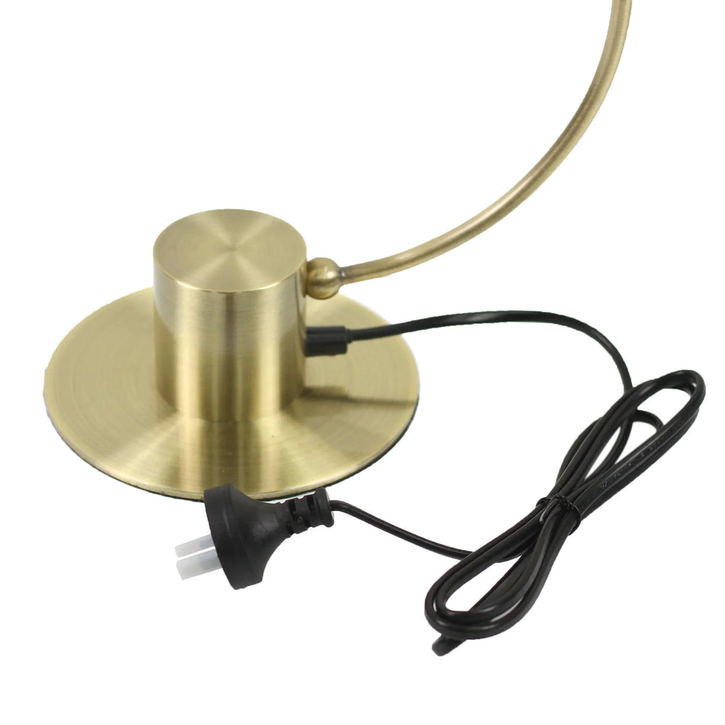 Brushed brass lamp base with black power cord and plug on white background