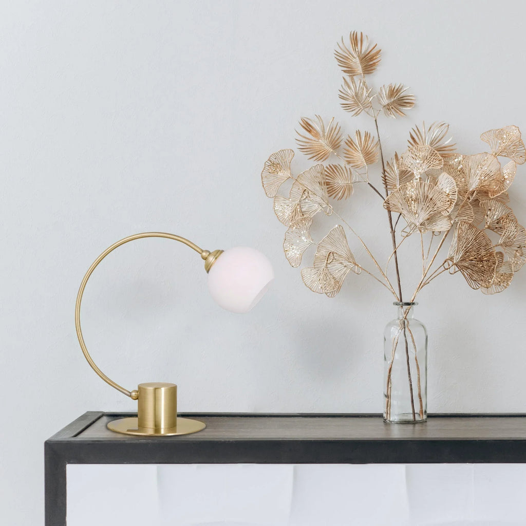 Modern gold table lamp and metallic decorative leaves in glass vase on a minimalist console