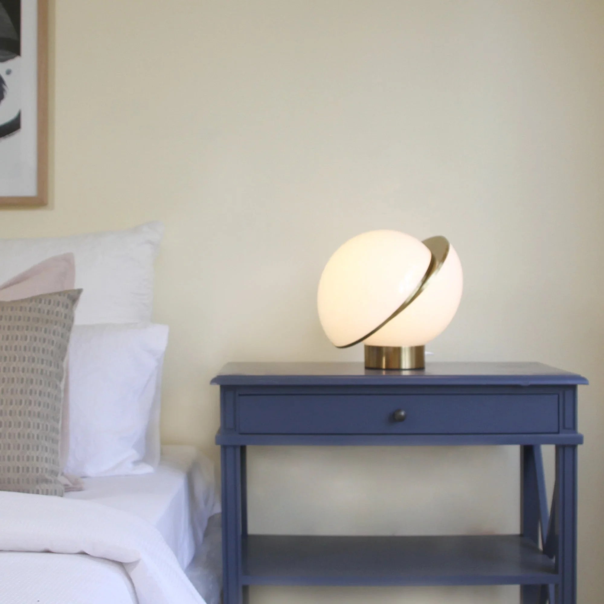 Modern globe table lamp on blue nightstand in cozy bedroom setting