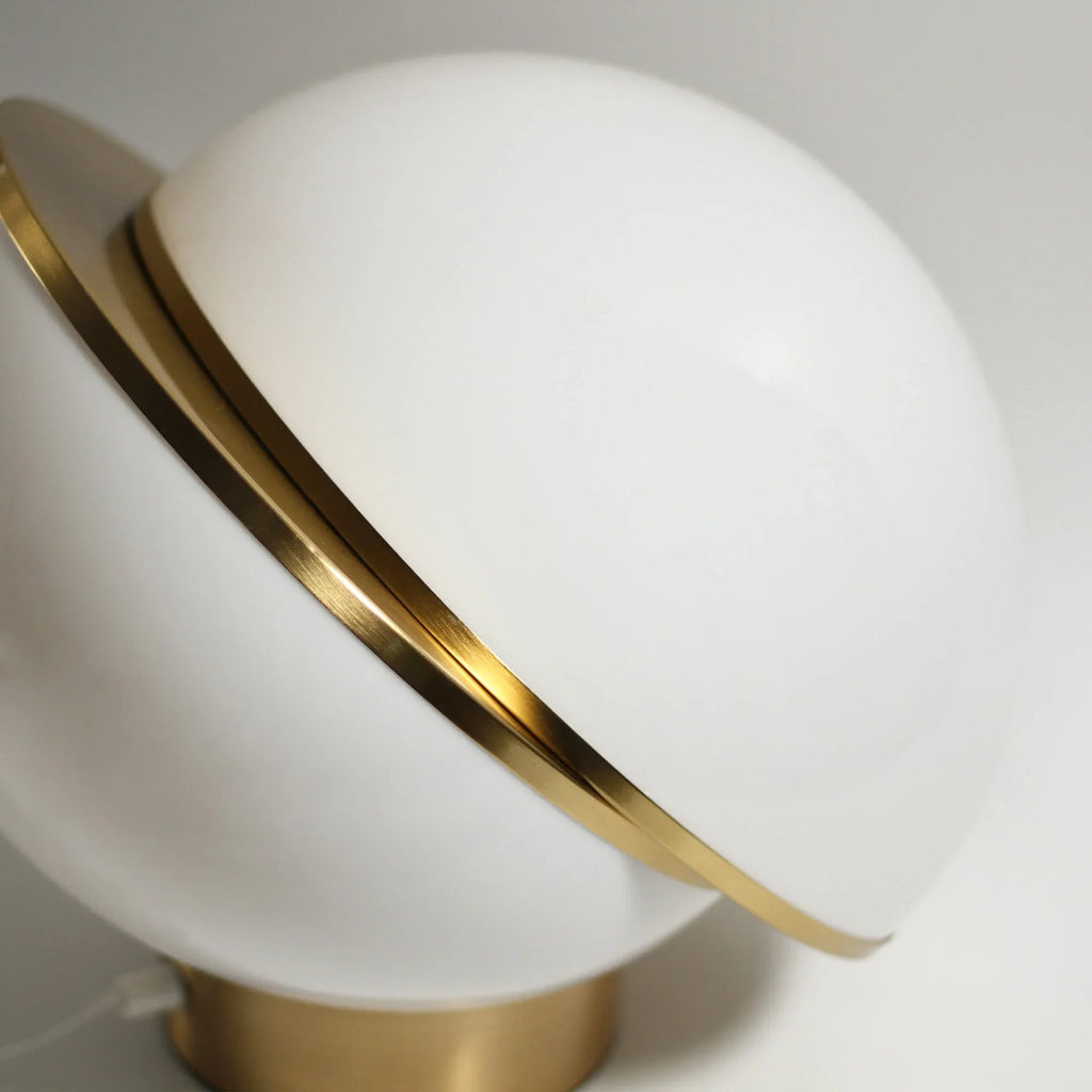 Modern white globe table lamp with gold metal accent on a brass base