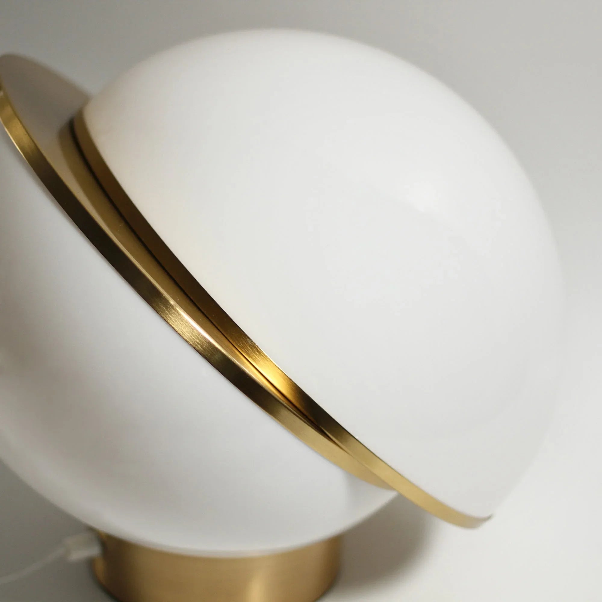 Modern white globe table lamp with gold metal accent on a brass base