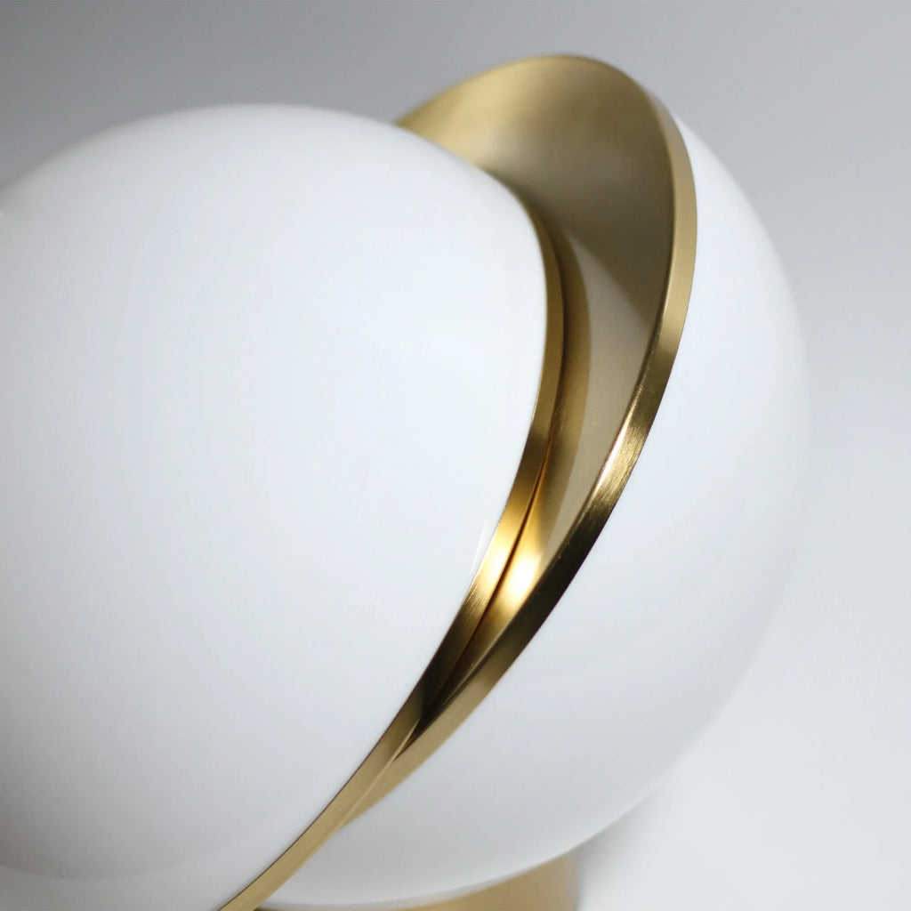 Modern white globe lamp with gold metal accent on a neutral background