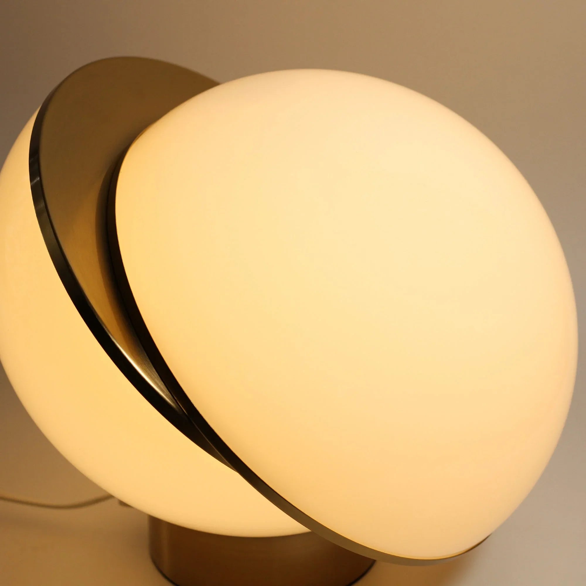 Modern spherical table lamp with frosted glass shade and brass accent glowing warmly